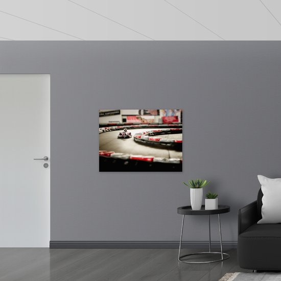 WallClassics - Poster Glanzend – Karter op Indoor Kartbaan - 100x75 cm Foto op Posterpapier met Glanzende Afwerking