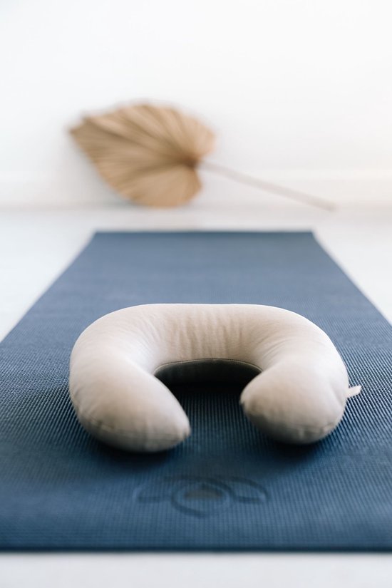 Donkerblauwe yogamat met subtiel lotuslogo, met daarop een wit, hoefijzervormig nekkussen.