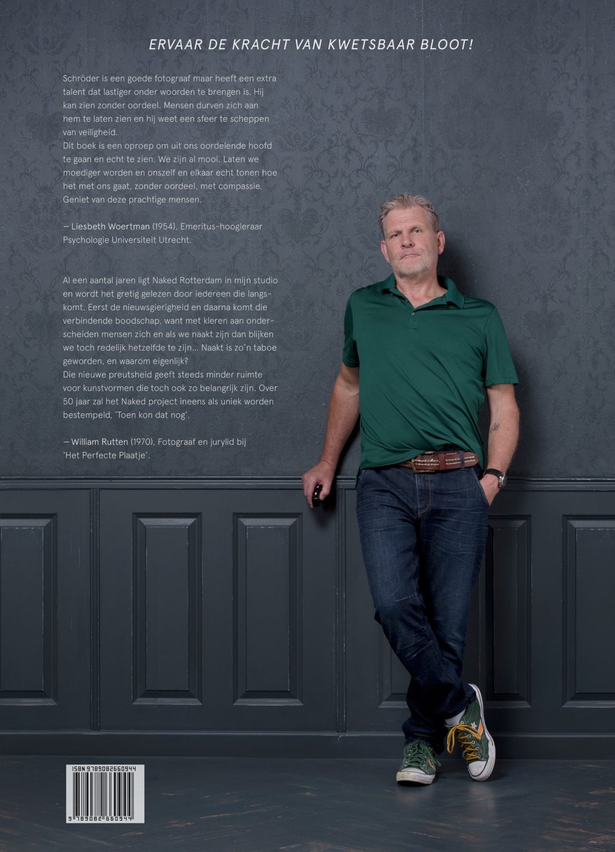 Leon Schröder, fotograaf, in groen shirt, spijkerbroek en sneakers, leunt tegen een donkergrijs wandpaneel.