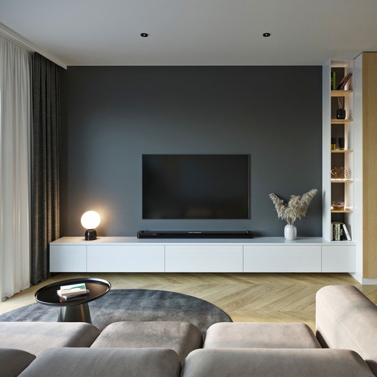 Moderne woonkamer met een grote zwarte tv aan de muur, gemonteerd op een lage witte kast.