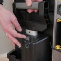 Grijze handgreep wordt op de zwarte gereedschapskoffer geplaatst met een duimbalkje.