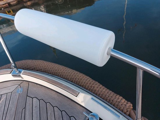 Wit relingkussen op een metalen reling, aan de zijkant van een boot met houten dek.