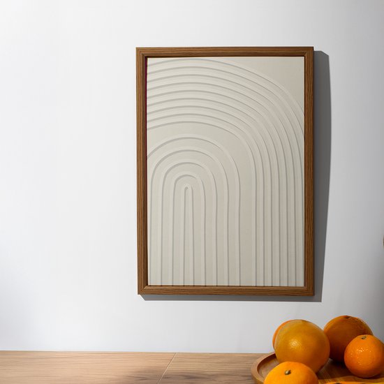 Een beige poster met gebogen lijnen in een houten lijst, naast een fruitschaal met sinaasappels.
