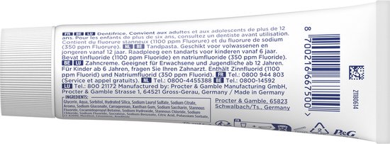 Linkerzijkant van een tube tandpasta met productinformatie en ingrediëntenlijst in meerdere talen.