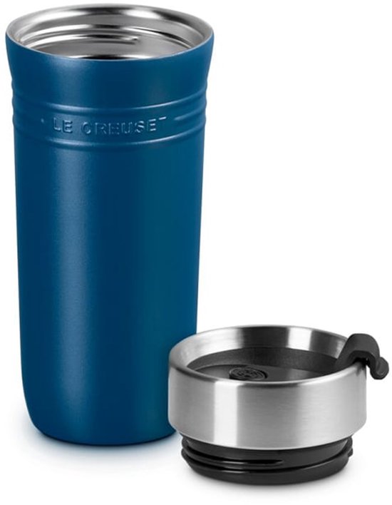 Een diepblauwe Le Creuset beker met zilverkleurig deksel ernaast.