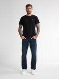 Man in zwarte T-shirt en donkerblauwe jeans.