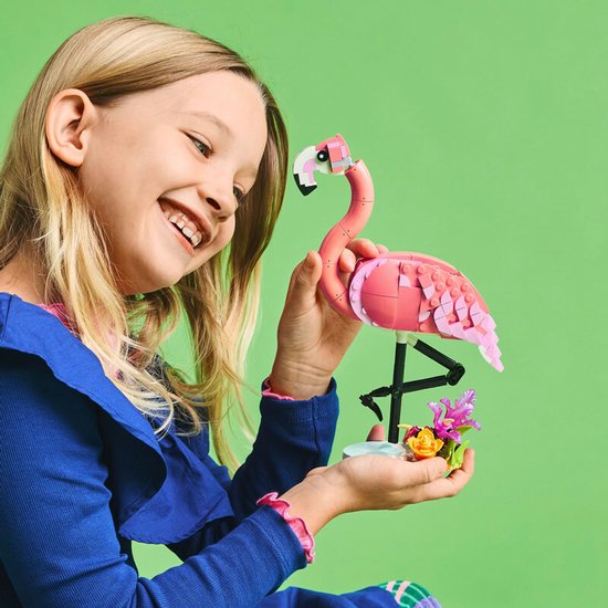Lachend meisje met een roze LEGO flamingo in haar handen.