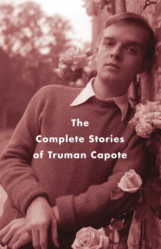 Een jongeman in een trui en wit overhemd, leunend tegen een bakstenen muur, omringd door rozen. De tekst 'The Complete Stories of Truman Capote' staat op de voorgrond.