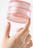 Hand die een Medicube Triple Deep Erasing Cream pot vasthoudt, die huidelasticiteit en helderheid verbetert.