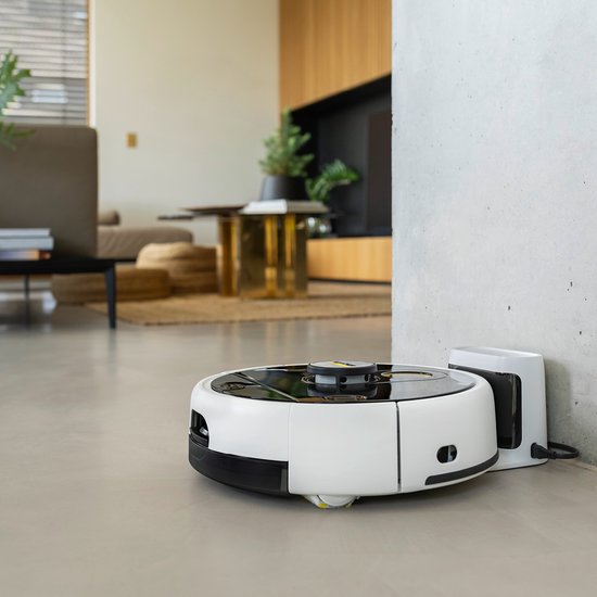 Witte Kärcher robotstofzuiger met zwarte bovenkant, aan de oplader in een woonkamer.