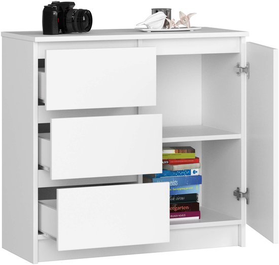 Witte ladekast met 3 gesloten lades en een gesloten deur. Camera en decoratie bovenop.