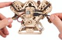 Achterkant van een houten V8-motor model met zichtbare elektronica en kabels, vastgehouden door twee handen.