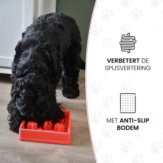 Zwarte hond eet uit rode voerbak met anti-slip bodem. Teksten "VERBETERT DE SPIJSVERTERING" en "MET ANTI-SLIP BODEM".