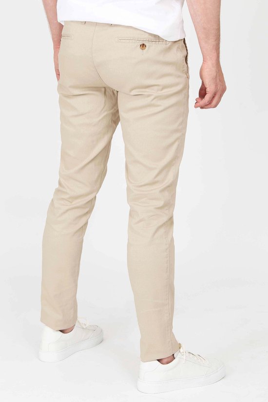 Achterkant van een mannen chino in lichtbeige, gedragen met witte sneakers.