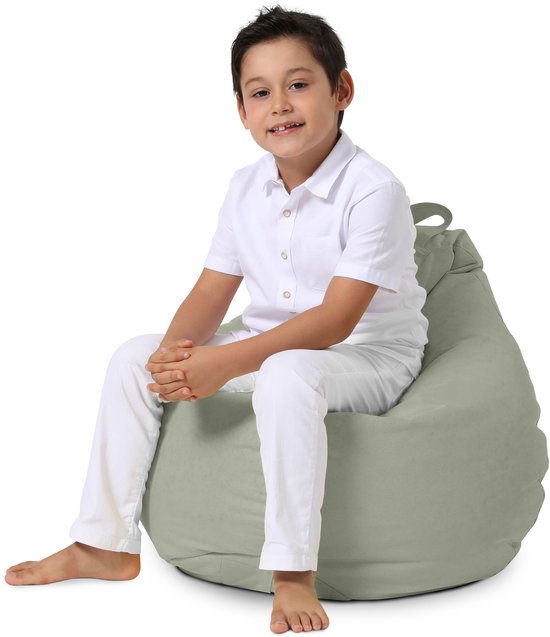 Jongen in wit overhemd en witte broek zit op een grijze zitzak.