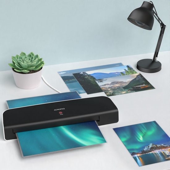 ACROPAQ lamineerapparaat op een bureau met een plant, bureau lamp en foto's die gelamineerd worden.