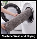 Een donkergrijs badmatje wordt in een wasmachine geplaatst.