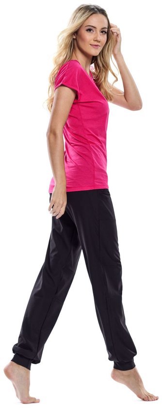 Model in een zwarte, nauwsluitende joggingbroek, wandelend naar voren. Ze draagt een felroze T-shirt.