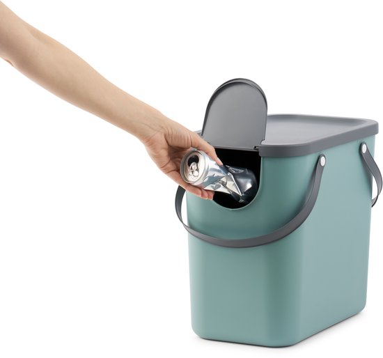 Hand doet een geplette frisdrankblik in een turquoise afvalbak met donkergrijs deksel en hengsels.