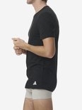 Man in zwart Adidas T-shirt en grijze boxershort, van de zijkant gezien.