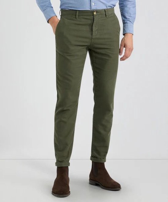 Man van voren, draagt een olijfgroene chino broek met opgerolde pijpen.