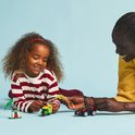 Een vrouw en een kind spelen met LEGO-voertuigen op een blauwe achtergrond.