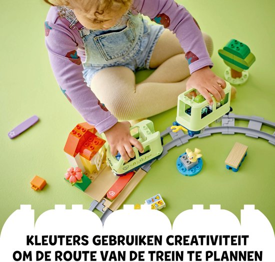 Un jeune enfant joue avec un train et des rails LEGO Duplo vert clair.