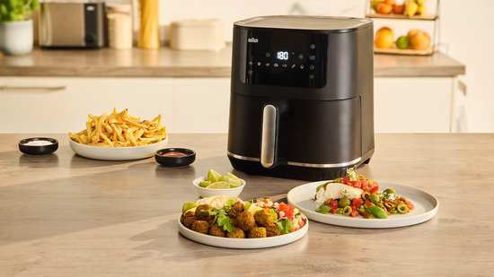 Zwarte Braun heteluchtfriteuse met digitale display. Naast de friteuse staan een schaal met frietjes, een bakje met saus en een schaal met falafel.