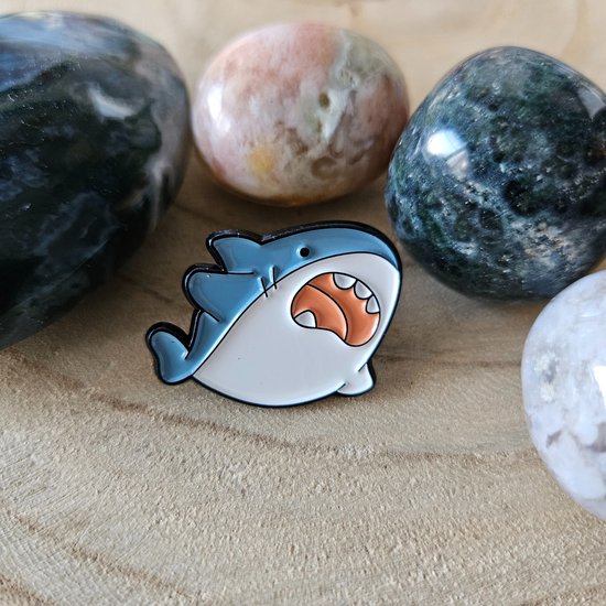 Broche émaillée bleu et blanc, en forme de requin, avec une grande bouche et des dents pointues.