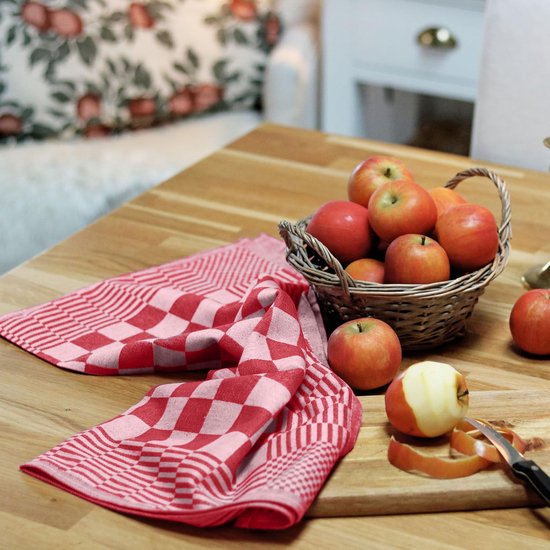 Rood-wit geblokt keukendoek op een houten tafel, naast een mand met appels.