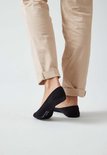 Zwarte onzichtbare sokken op de voeten van een vrouw met beige broek.