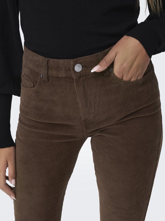 Close-up van een vrouw in bruine corduroy broek, hand in de zak.