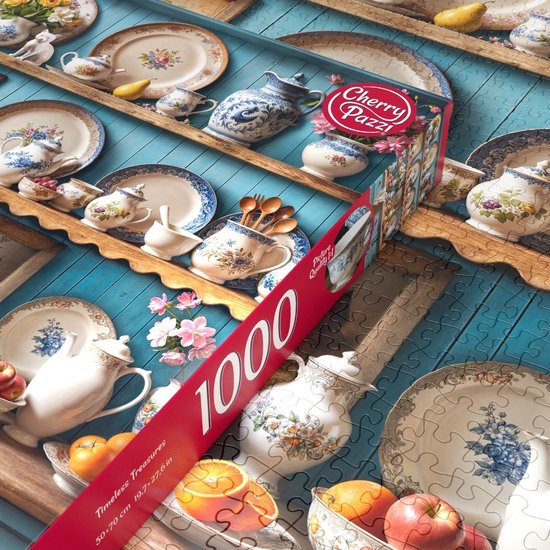 Een 1000-delige puzzel met antiek servies, fruit en bloemen op blauwe planken. De puzzel is deels gelegd.