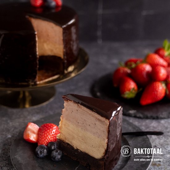 Chocoladetaart met een laag glanzende chocolade ganache en een stuk verwijderd, met aardbeien en bosbessen.