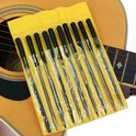 Tien vijlen met zwarte handvatten in een gele plastic verpakking, liggend op een akoestische gitaar.