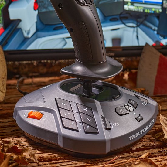 Grijze joystick op een tafel, met een deel van een monitor met een spel op de achtergrond.