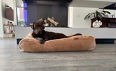 Bruin corduroy hondenbed met een bruine labrador die languit ligt te rusten.