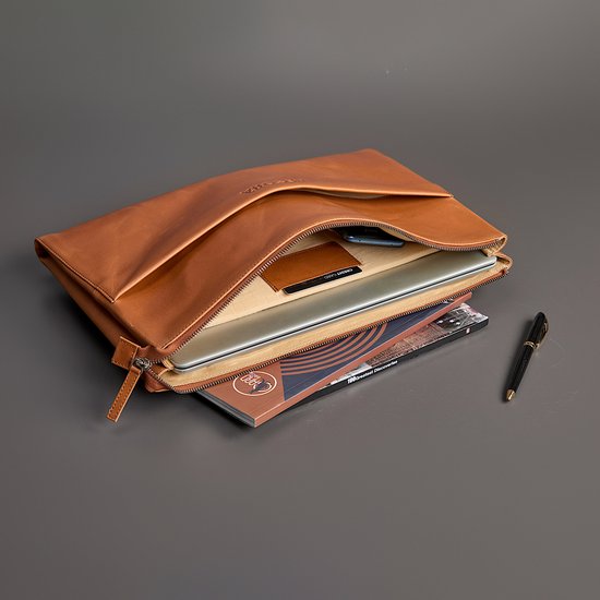 Cognacbruine leren laptoptas open met daarin een laptop, tijdschrift en pen.