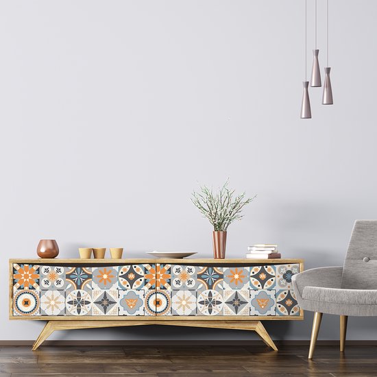 Houten dressoir met cementtegelstickers, koperen vaas, mokjes en een grijze fauteuil.