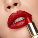 Close-up van een mond met volle rode lippen, waarbij een gouden huls met rode lippenstift wordt aangebracht.