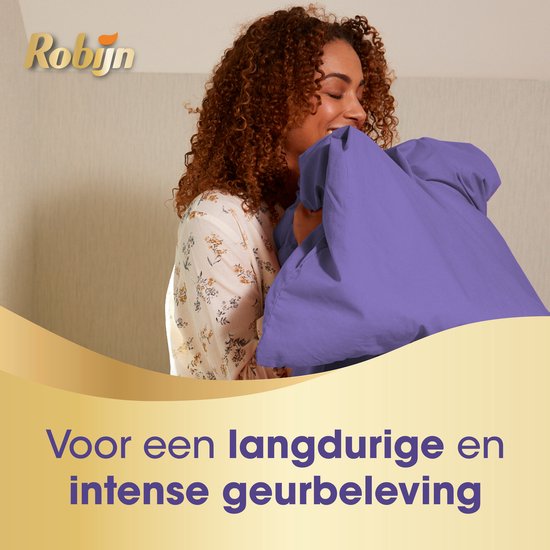 Vrouw met krullend haar die een paars laken ruikt.