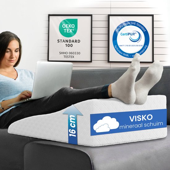 Vrouw op een bank met laptop en sokken, benen rustend op een wit wigkussen. Textuurdetail en "Visco mineraal schuim".