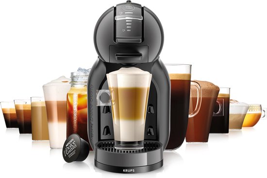 Machine à café Krups Mini Me noire avec diverses boissons au café Dolce Gusto à l'arrière-plan.