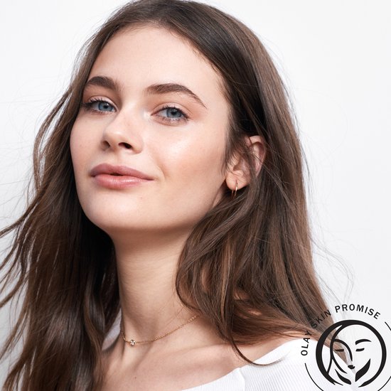 Jong model met bruin haar en blauwe ogen, draagt een witte trui. Rechtsonder Olay Skin Promise logo.