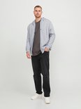 Man draagt een grijze open rits hoodie over een donkergrijs T-shirt en zwarte jeans.