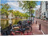 Vlag - Rij Fiets Geparkeerd langs de Gracht in Amsterdam - 80x60 cm Foto op Polyester Vlag