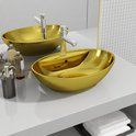 Lavabo ovale doré avec robinet chromé, entouré de flacons et de serviettes.