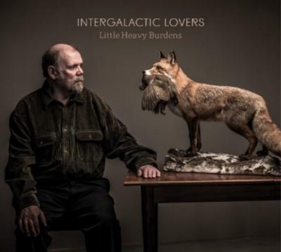 Een man met baard kijkt naar een vos met een vogel in zijn bek. Albumtitel: Intergalactic Lovers - Little Heavy Burdens.