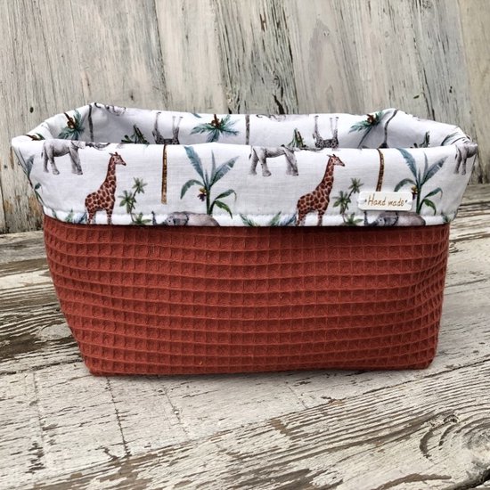 Roestbruin mandje met wafelstructuur. Binnenzijde met jungleprint van giraffen, olifanten en palmbomen. Tekst 'Hand made'.