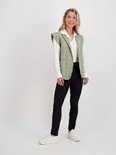 Model met zwarte slim fit broek, gestreept gilet en witte blouse.